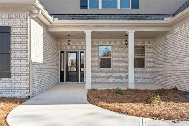 property entrance with covered porch and brick siding