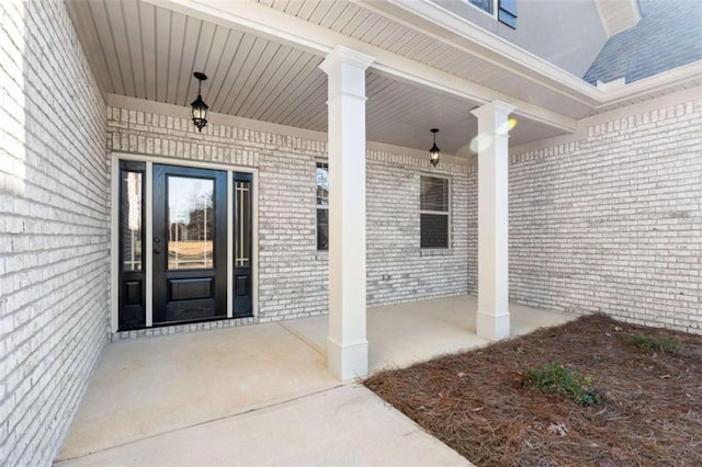 entrance to property with covered porch and brick siding