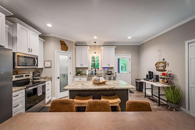 kitchen with white cabinets, a breakfast bar area, stainless steel appliances, and ornamental molding