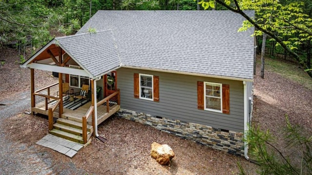 exterior space featuring a wooden deck and a shingled roof