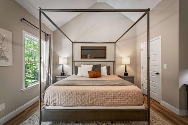 bedroom with lofted ceiling, baseboards, and wood finished floors