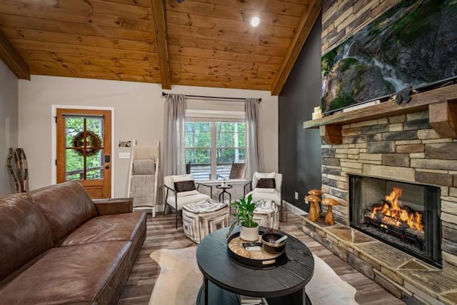 living area featuring wood ceiling, wood finished floors, a stone fireplace, and vaulted ceiling with beams