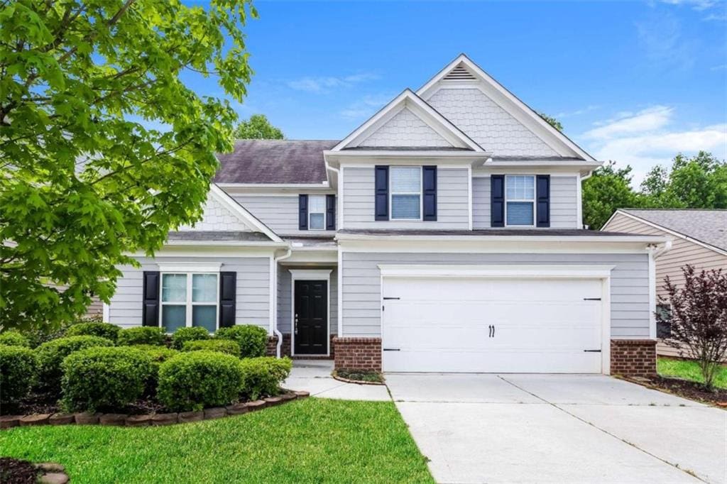 craftsman-style home featuring driveway, brick siding, and an attached garage