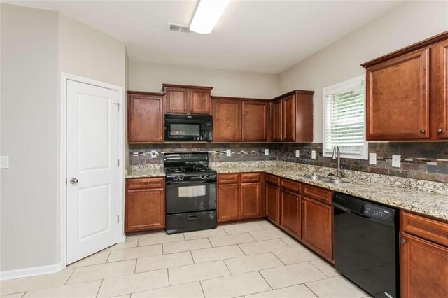 kitchen with light tile patterned floors, sink, tasteful backsplash, black appliances, and light stone counters