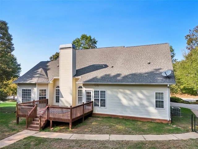 back of house with roof with shingles, a chimney, fence, and a wooden deck