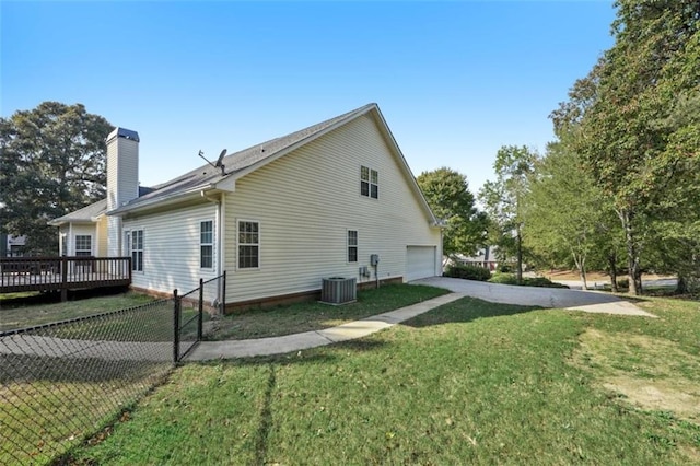 view of side of home featuring a yard, a chimney, concrete driveway, an attached garage, and fence