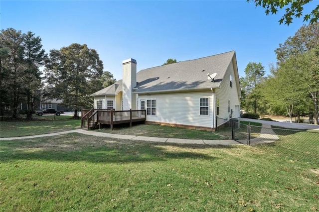 rear view of property with fence, a chimney, a wooden deck, and a lawn