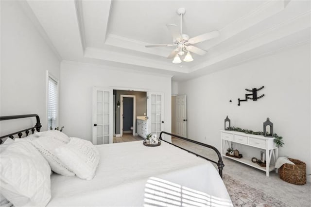 bedroom featuring light carpet, a tray ceiling, a ceiling fan, and ornamental molding