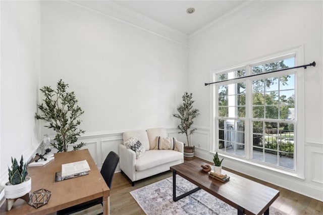 interior space with a wainscoted wall, a decorative wall, wood finished floors, and crown molding