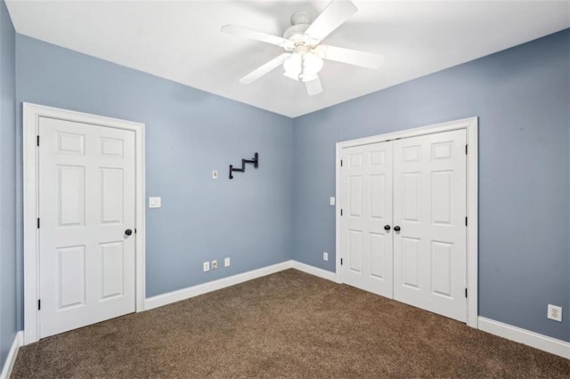 unfurnished bedroom featuring a ceiling fan, baseboards, dark colored carpet, and a closet