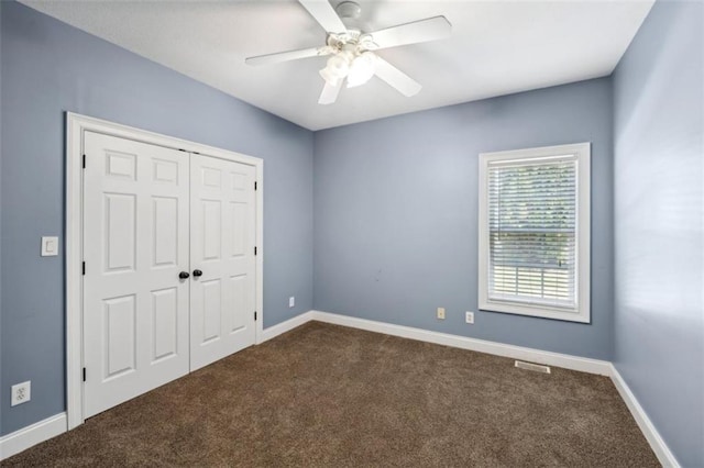 unfurnished bedroom featuring dark colored carpet, a closet, visible vents, and baseboards