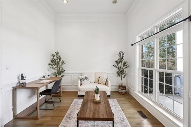 interior space featuring wainscoting, visible vents, crown molding, and light wood-style flooring