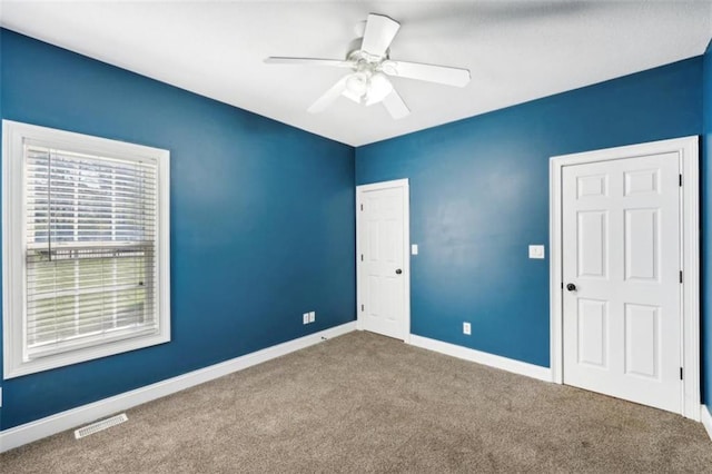 carpeted spare room with visible vents, ceiling fan, and baseboards