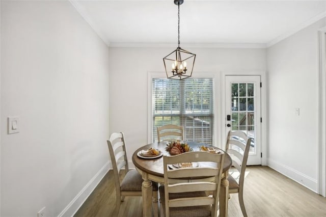 dining space with a chandelier, ornamental molding, light wood-style flooring, and baseboards