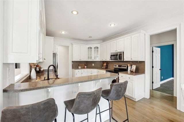 kitchen featuring appliances with stainless steel finishes, a breakfast bar, a peninsula, a sink, and backsplash