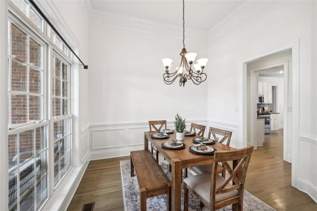 dining area with visible vents, a decorative wall, wood finished floors, and ornamental molding