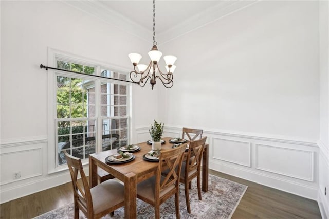 dining room featuring a notable chandelier, a decorative wall, dark wood-type flooring, and wainscoting