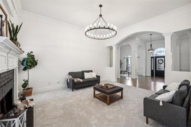 carpeted living area featuring arched walkways, ornate columns, ornamental molding, a brick fireplace, and baseboards