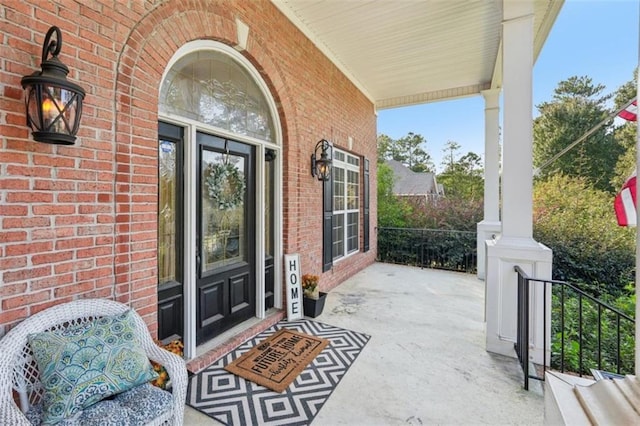 doorway to property with a porch and brick siding