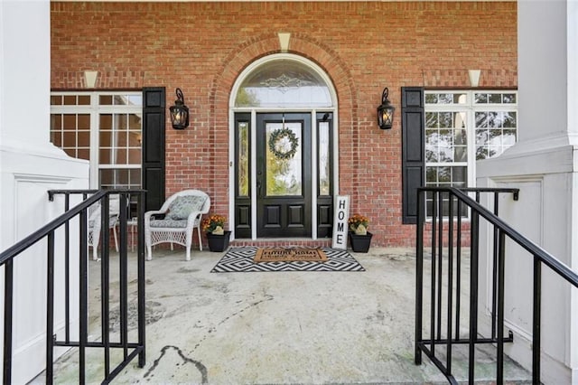 doorway to property with a porch and brick siding