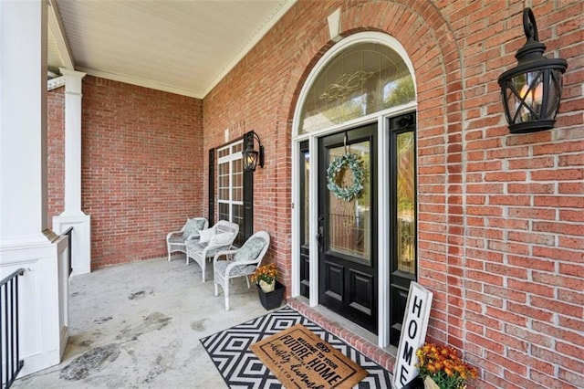 property entrance with a porch and brick siding