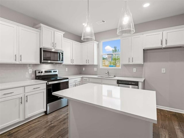 kitchen featuring hanging light fixtures, dark hardwood / wood-style floors, a kitchen island, white cabinetry, and stainless steel appliances