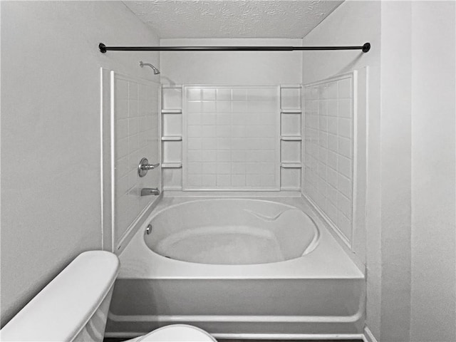 bathroom featuring toilet, a textured ceiling, and bathing tub / shower combination