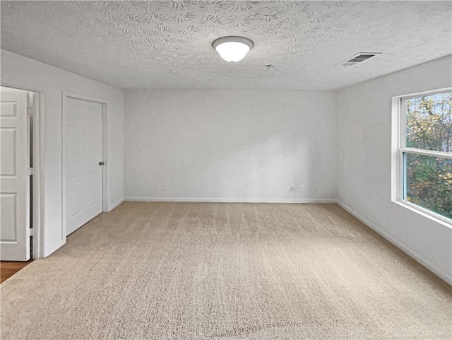 carpeted spare room with a textured ceiling