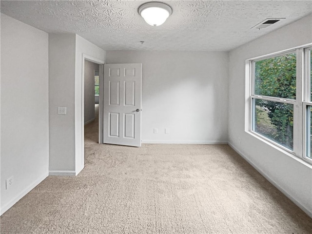 spare room featuring light carpet and a textured ceiling