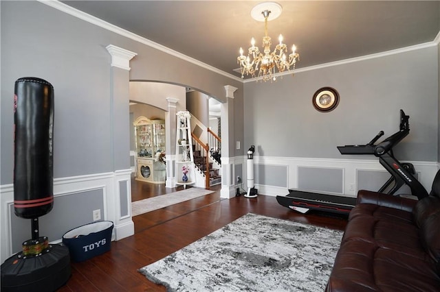 living area with crown molding, arched walkways, wood finished floors, a wainscoted wall, and ornate columns