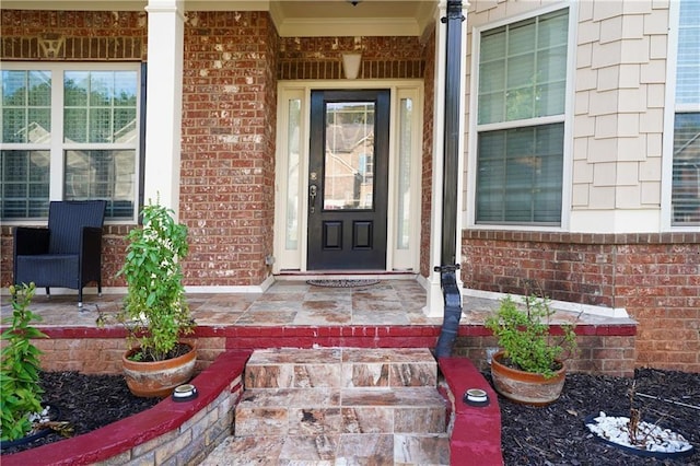 doorway to property featuring covered porch and brick siding