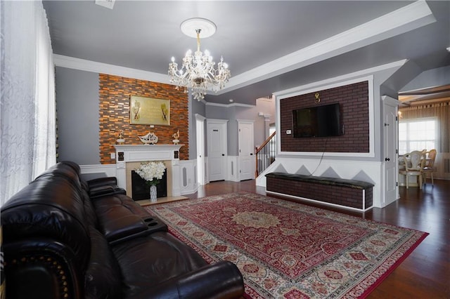living room with a chandelier, ornamental molding, wood finished floors, and a wainscoted wall