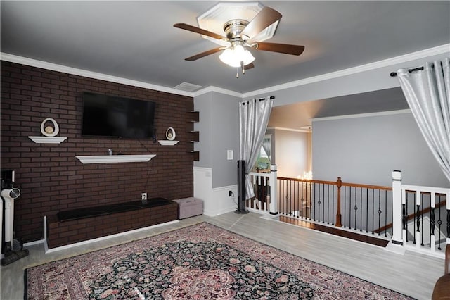 living room featuring crown molding, ceiling fan, wainscoting, and wood finished floors