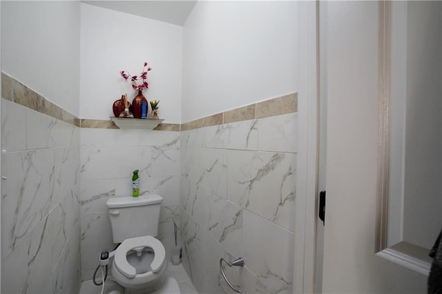 bathroom featuring toilet, tile walls, and a wainscoted wall
