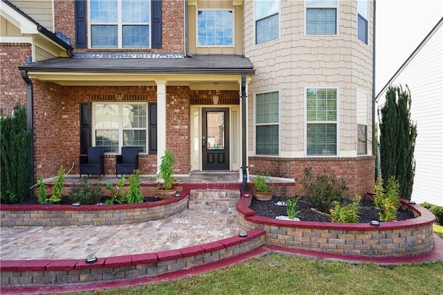 entrance to property with a porch and brick siding