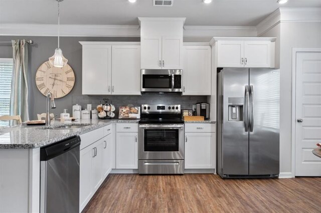 kitchen featuring stainless steel appliances, a sink, crown molding, a peninsula, and white cabinets