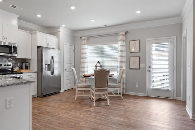 dining space featuring crown molding, wood finished floors, baseboards, and recessed lighting