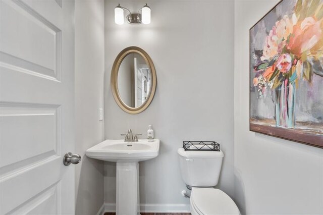 half bath with toilet and baseboards