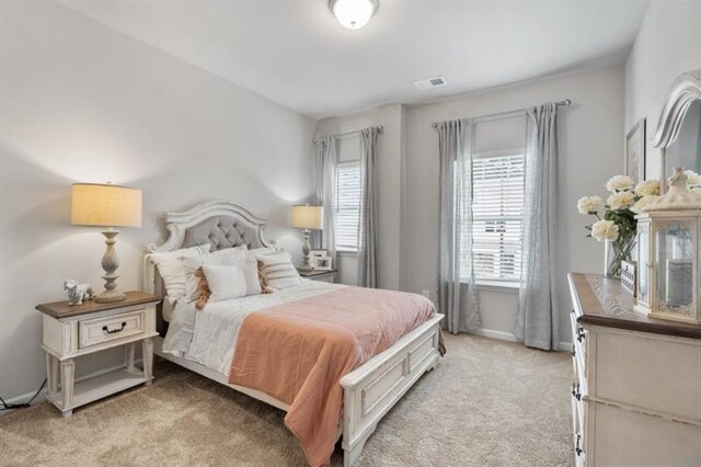 bedroom with light carpet, multiple windows, and baseboards