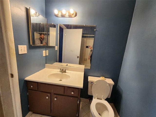 bathroom with toilet, vanity, and tile patterned flooring