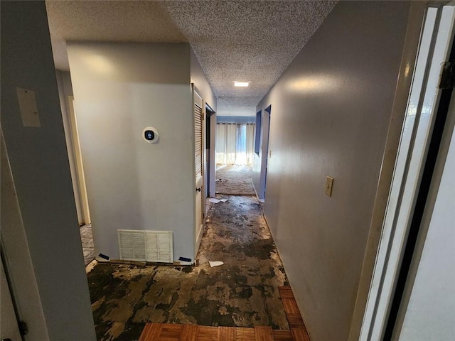 hall featuring a textured ceiling and visible vents