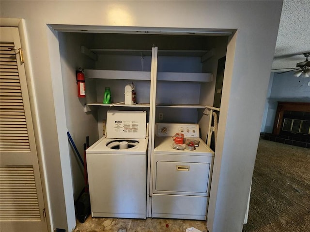 laundry area featuring laundry area, washer and clothes dryer, a glass covered fireplace, and a ceiling fan