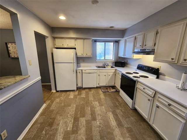 kitchen with white appliances, dark wood-style flooring, light countertops, under cabinet range hood, and a sink