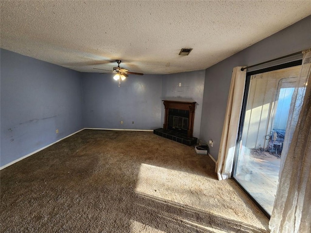 unfurnished living room with ceiling fan, a tiled fireplace, a textured ceiling, and carpet flooring