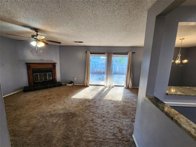 unfurnished living room featuring carpet flooring, a textured ceiling, a tile fireplace, baseboards, and ceiling fan with notable chandelier