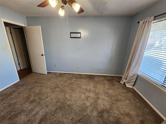 empty room with a textured ceiling, dark colored carpet, and ceiling fan