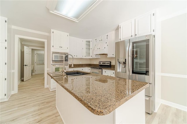4120 Grady Smith Rd, Loganville, GA 30052 - kitchen featuring appliances with stainless steel finishes, custom range hood, a kitchen island with sink, white cabinets, and light wood-type flooring