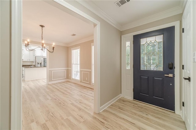 4120 Grady Smith Rd, Loganville, GA 30052 - foyer with a chandelier, ornamental molding, light wood finished floors, a decorative wall, and wainscoting