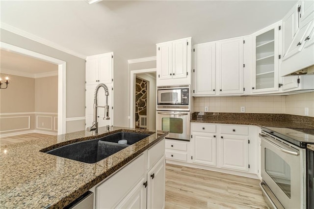 4120 Grady Smith Rd, Loganville, GA 30052 - kitchen with stainless steel appliances, dark stone countertops, under cabinet range hood, white cabinets, and glass insert cabinets