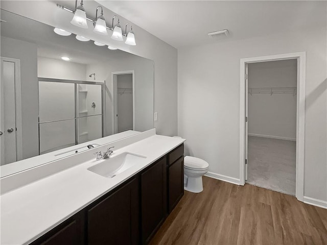 bathroom with hardwood / wood-style floors, vanity, toilet, and walk in shower